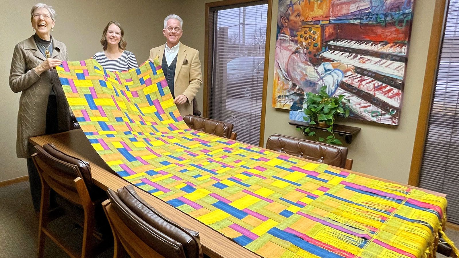Sara Nordling, left, displays her tapestry to Heatland Sings Associate Artistic Director Natalie Young and Maestro Robert Nance.